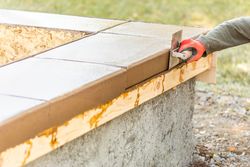 Construction Worker Using Stainless Steel Edger On Wet Cement Forming Coping Around New Pool