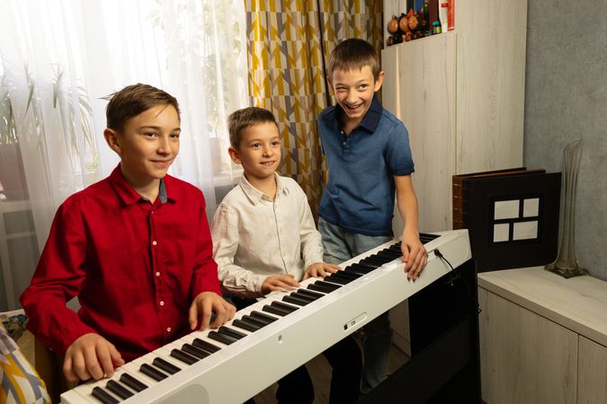 Three boys at the piano, smiling and having fun