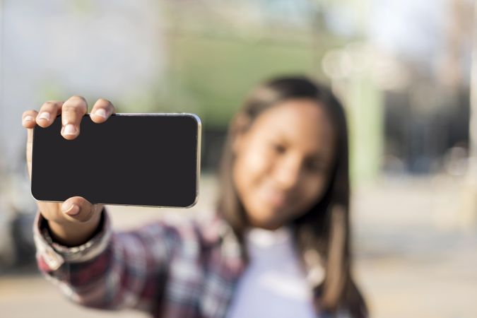 Mock up screen of smartphone with woman taking selfie in background