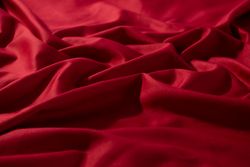 Crumpled wavy Red silky fabric background texture.
