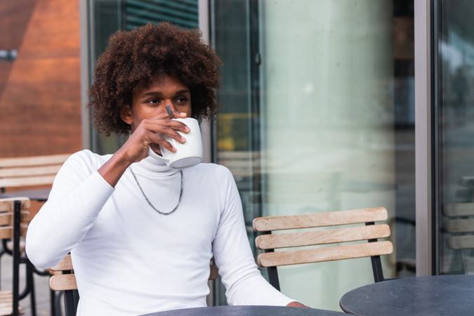 Pensive young Black man drinking coffee and looking away in cafe