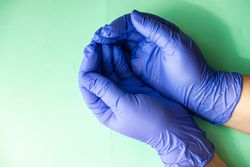 Looking down at green table with cupped hands in blue latex gloves