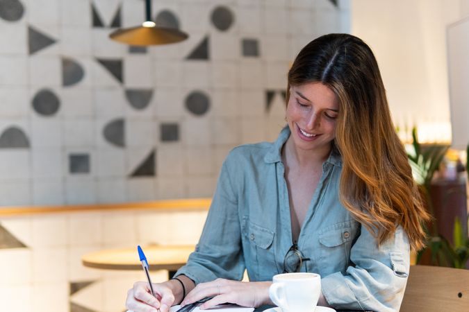 Dreamy woman with notebook and tea in cafe