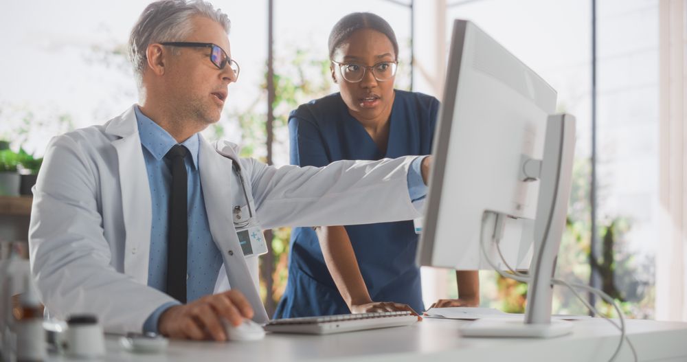 Doctor's Office: Physician Talks With Professional Head Nurse, Using Computer.