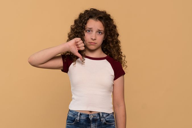 Young girl giving thumbs-down gesture, showing disapproval