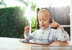 Blond boy using headphones and choosing music or show on digital tablet 4jLyR0