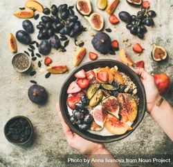 Woman and yogurt bowl over fruit assortment with figs, grapes, peaches, and chia seeds, square crop 56NQL5