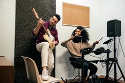 Man playing guitar and woman playing drums