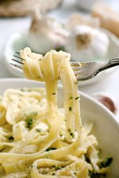 Cooked tagliatelle pasta with pesto sauce on fork