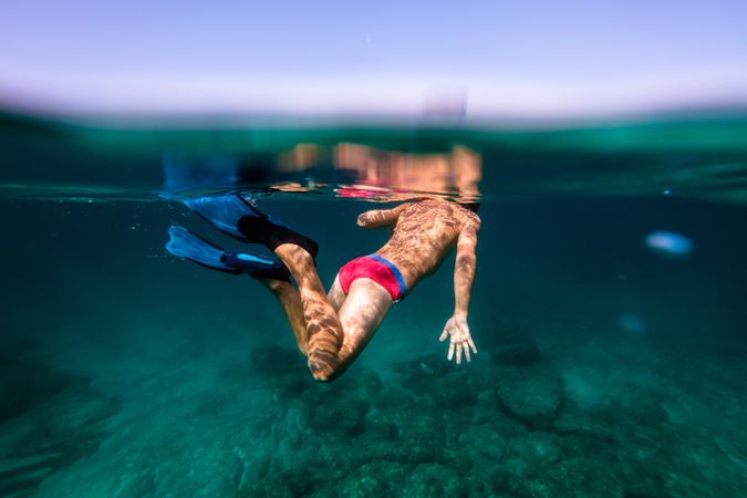 Teen swimmer floating in blue seawater in flippers