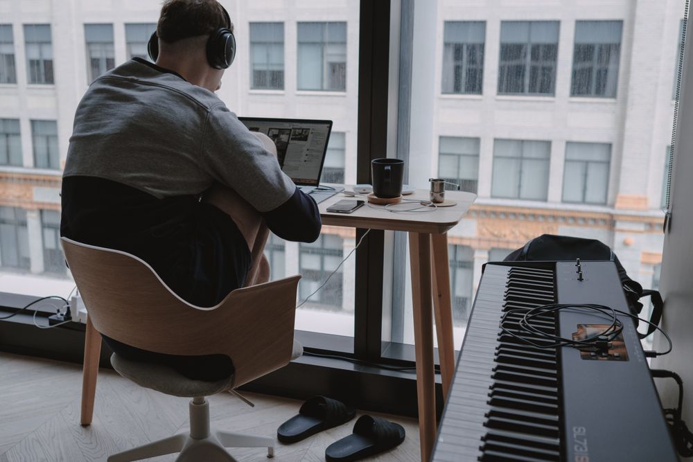Back view of young man creating music on computer