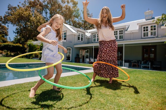 Mother and daughter playing with hula hoops in backyard