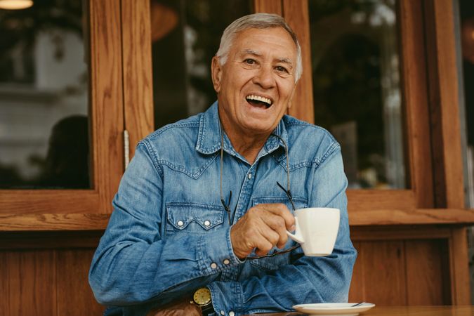 Portrait of cheerful man having coffee at cafe smiling and looking at camera