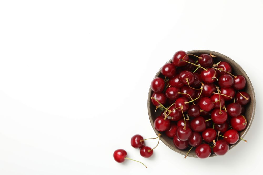 Ripe cherry fruits in a bowl on a light background
