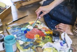 Close up of a woman making colors on a pallete.