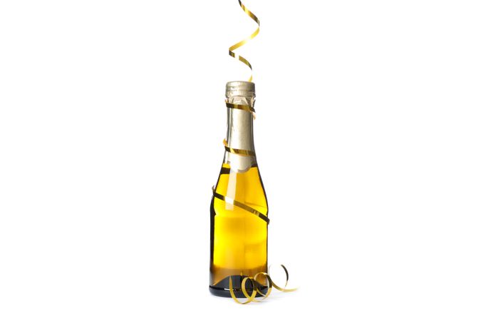 Mini champagne bottle with golden ribbon isolated on light background