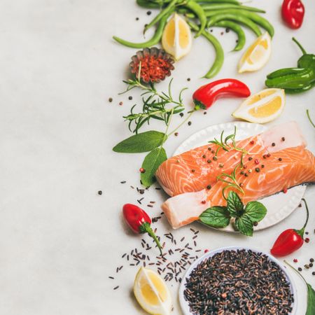 Top view of raw salmon fish fillet steaks with vegetables, greens, rice and spices