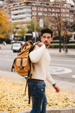 Trendy young male walking with backpack