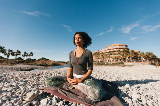Sportive woman sitting on sandy beach in asana