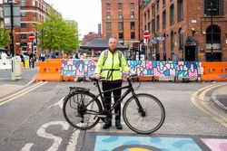 Older woman in neon wind breaker with her bicycle standing in the street