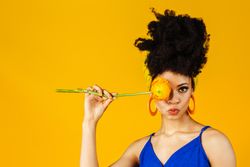 Portrait of Black woman with large earrings holding a rose over her eye