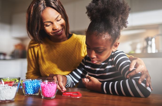 Smiling Black mother and daughter doing arts and crafts at home