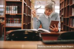 Woman sitting in a library reading a book bx7xX4
