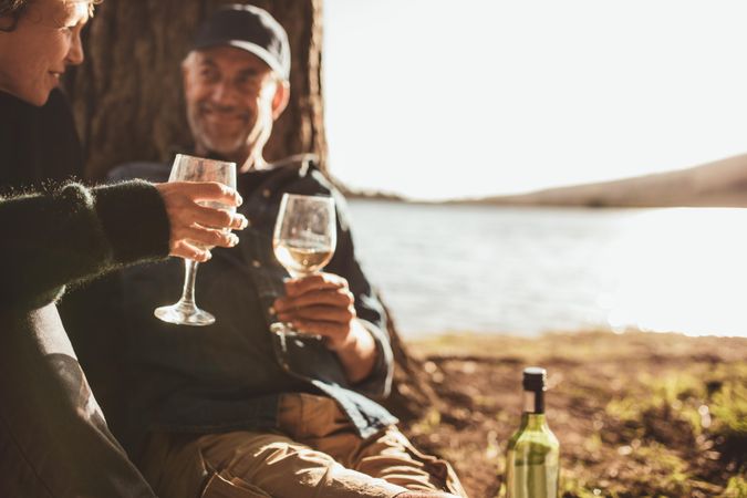 Close up portrait of romantic couple drinking wine while camping near a lake