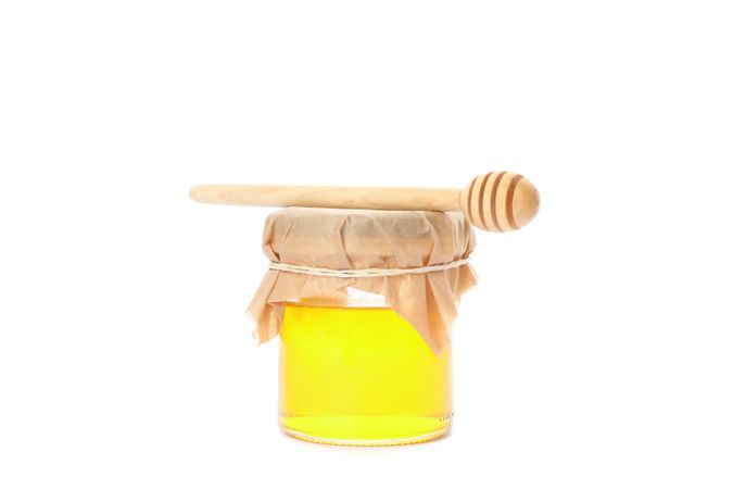 Dipper and glass jar with honey isolated on blank background