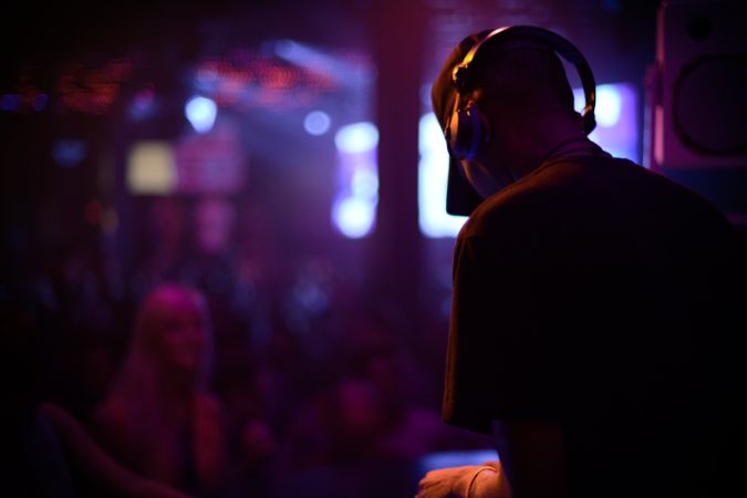 Dark image of man in headphones playing at night club