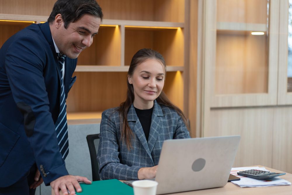 Male and female colleagues smiling over a laptop