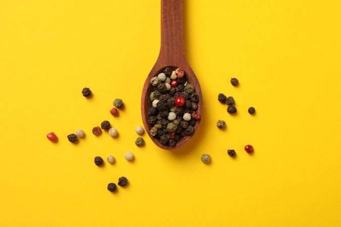Top view of wooden spoon with whole peppercorns