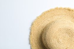 Pretty straw hat on neutral background. Space for text, top view