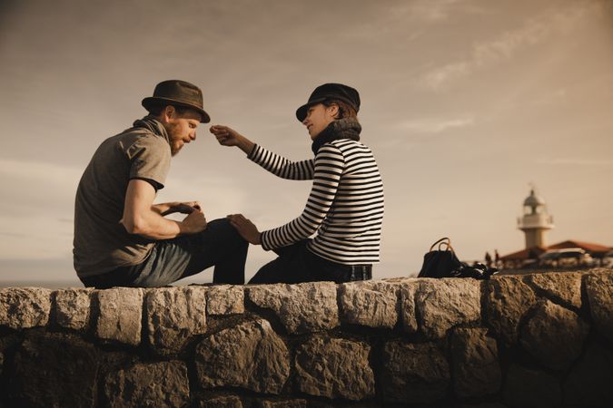 Man and woman on stones near lighthouse