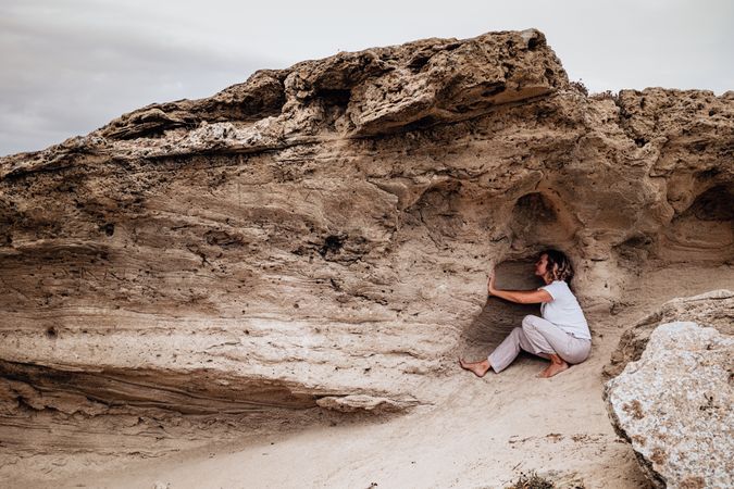 Barefoot woman meditating in rock cavity