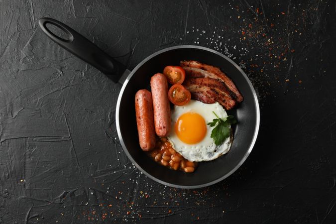 Top view of breakfast in pan with eggs, tomatoes, sausage and bacon