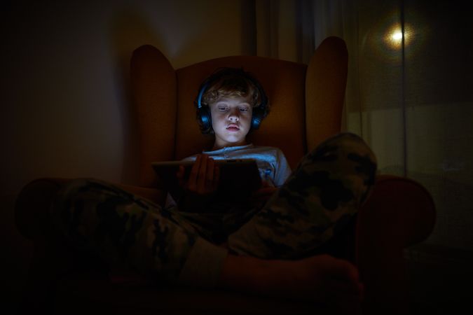 Boy playing on tablet at night
