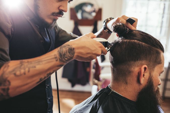 Barber using clippers to trim customer’s hair