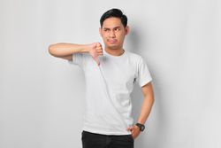 Asian male in grey studio making thumbs down