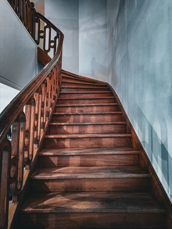 A wooden winding staircase in a stark white interior