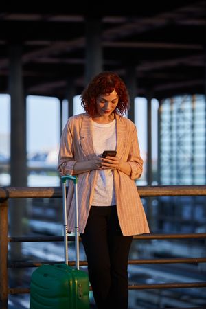 Smiling young woman browsing on phone at station