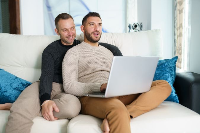 Two men relaxing on couch with laptop