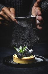 Hand holding a blackberry tartlet