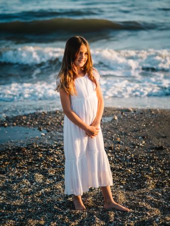 Smiling girl standing on seaside among waves