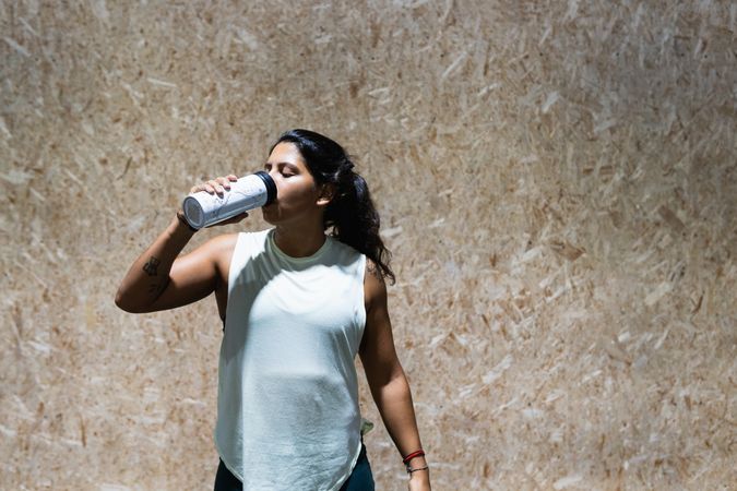 Hispanic woman drinking water in gym