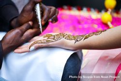 Person applying henna on woman's hand beB6G0