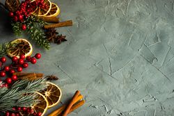 Christmas frame with fir tree, red berries and dried orange slices on grey background with copy space