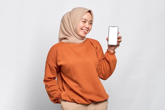 Muslim woman smiling at smart phone’s mock up screen