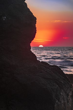 Colorful dusk seen from behind cliffs of rocky beach, beautiful
