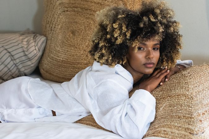 Thoughtful Black woman lying on bed in bedroom